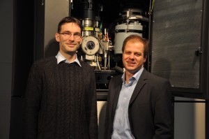 Dr. Benjamin Butz and Prof. Erdmann Spiecker in front of the aberration-corrected Titan3 80-300 which was employed for the microscopic investigation of defects in bilayer graphene. (Image: FAU)