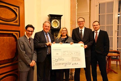 The Bavarian Minister for Health and Care Melanie Huml presents the official confirmation of 2.2 million euros in funding for the DigiDEM project to Prof. Dr. Elmar Gräßel from the Centre for Health Service Research at Universitätsklinikum Erlangen, Prof. Dr. Peter Kolominsky-Rabas from the Interdisciplinary Centre for Public Health at FAU, Marco Wendel from Medical Valley EMN e.v. and Michael Reichold from the Chair of Medical Informatics at FAU (from left).