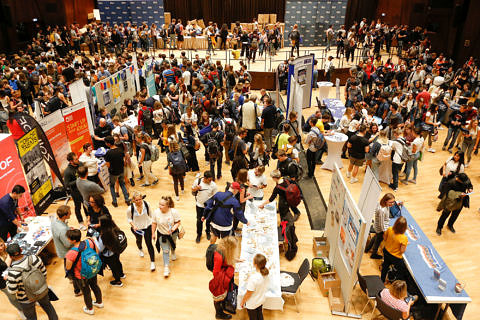 A large hall with many students and information stands.