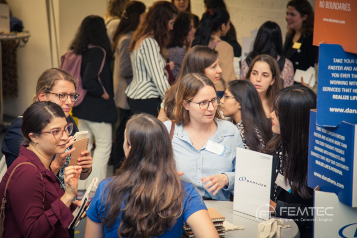 Women at a Femtec event networking in small groups.