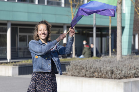 Photo of a young woman who is waving the rainbow flag