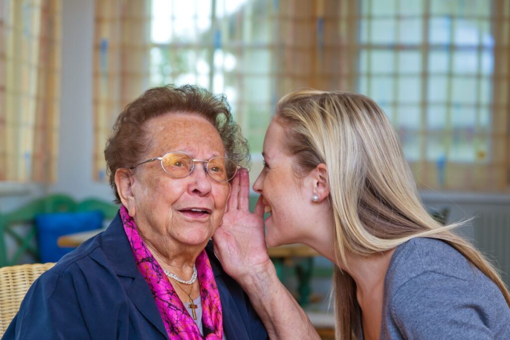 Young woman says something in older woman's ear
