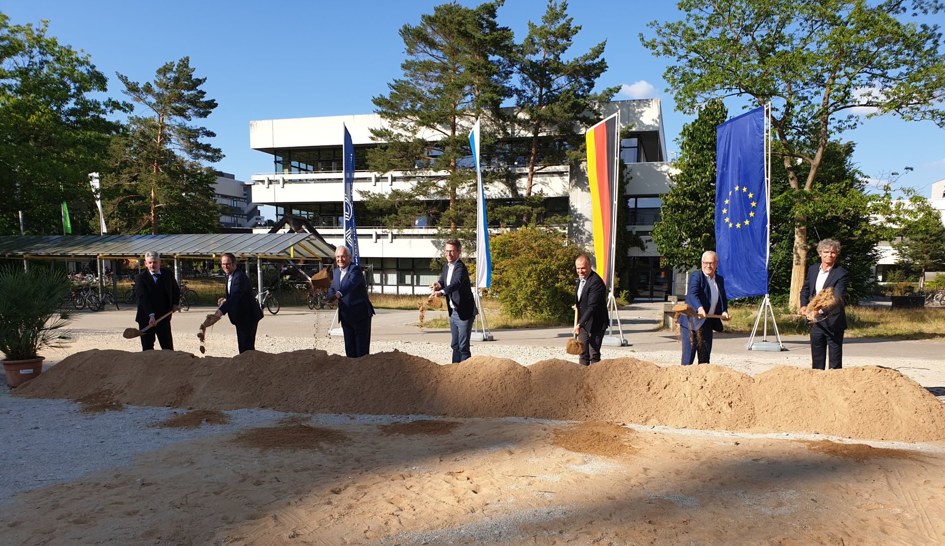 Men with spades in front of mound of earth in background flags of FAU, Bavaria, Germany, Europe