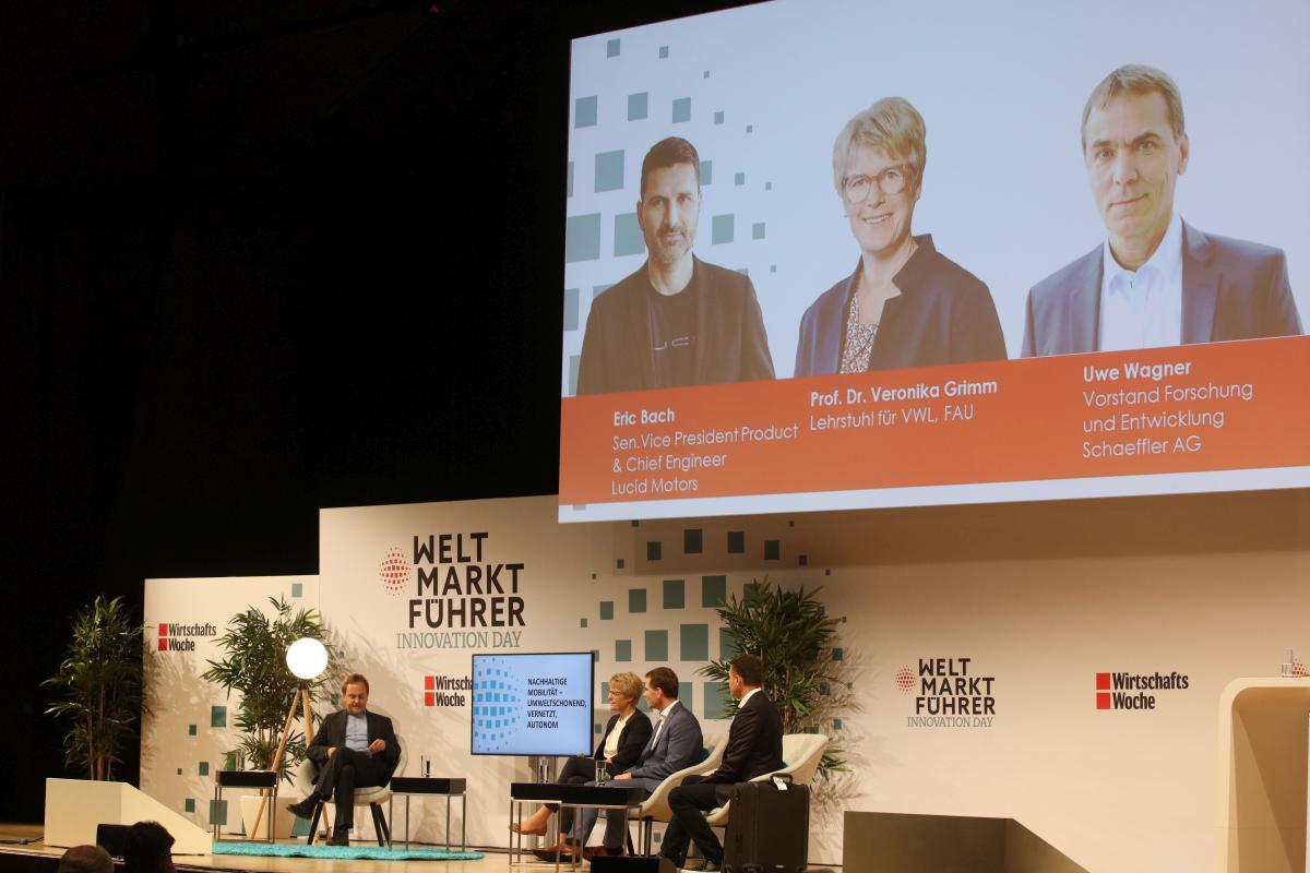 Speakers discussing sustainable mobility on stage.