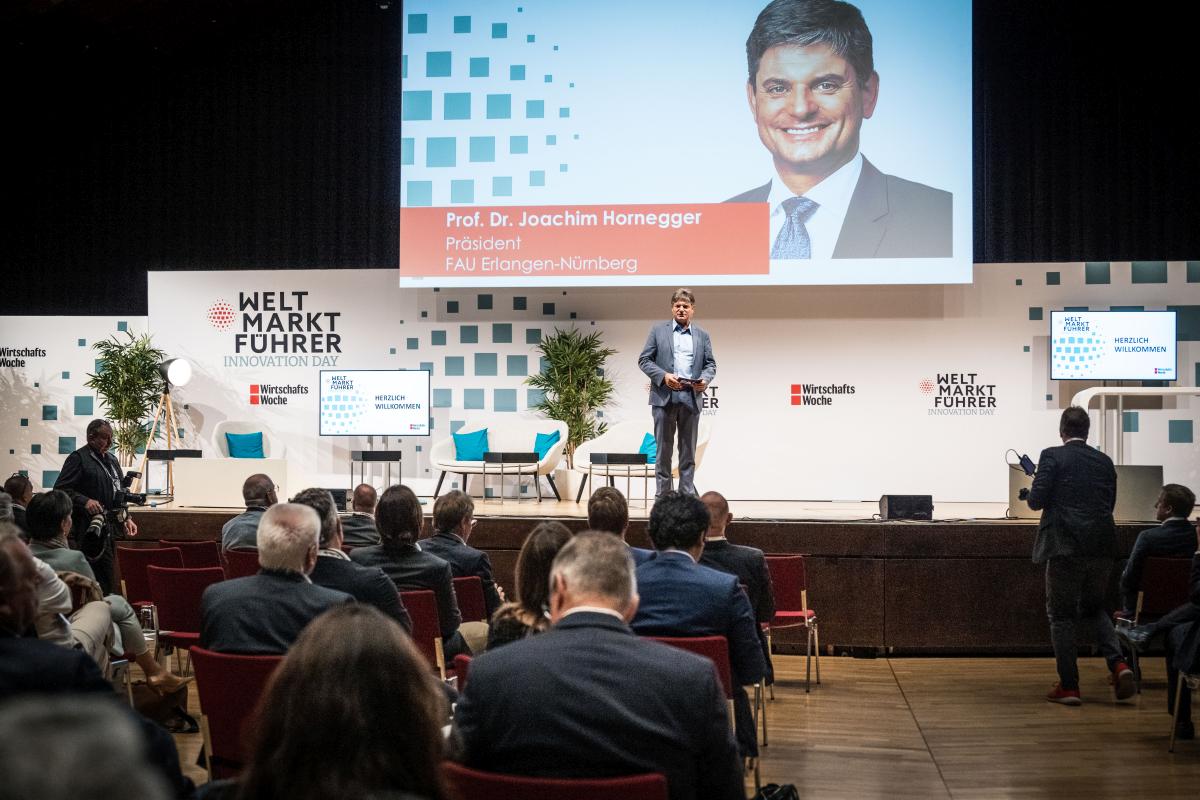 Standing in the middle of the stage infront of audience: FAU president Prof. Joachim Hornegger welcomes the guests.