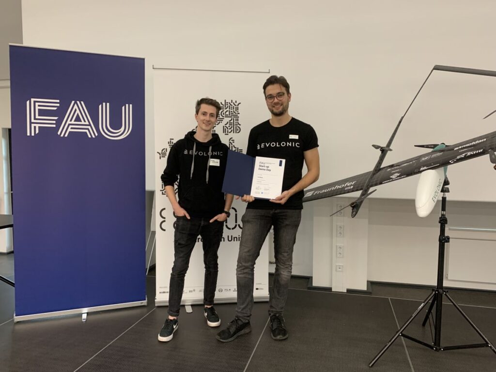 Photo of two man. One of them is holding a folder