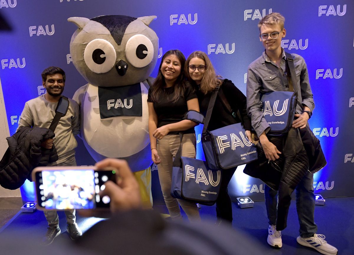 Four students and the FAU mascot stand in front of a wall and take a selfie.