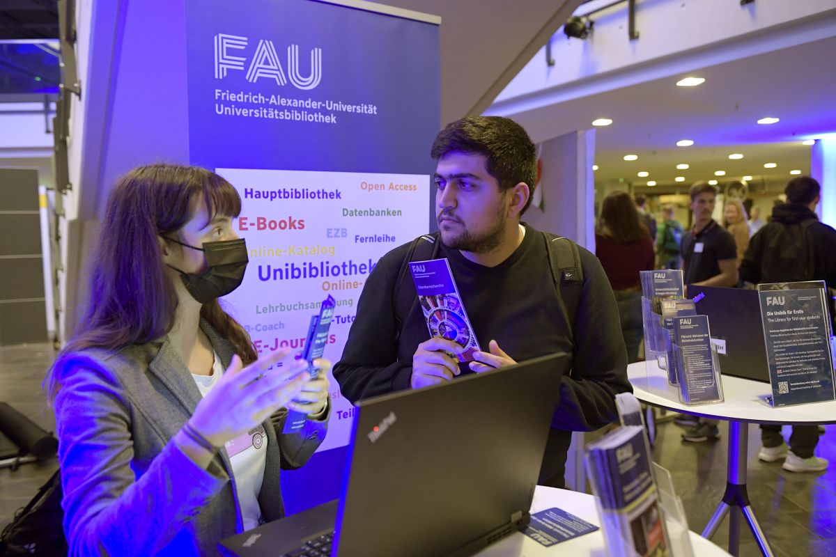 Two people standing in front of a computer and talking