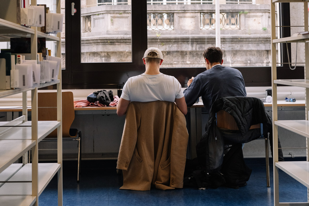 Two men in a library in front of a window