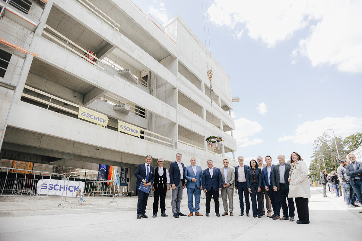 Important people stand ready for the group photo. The shell of the new building in the background.