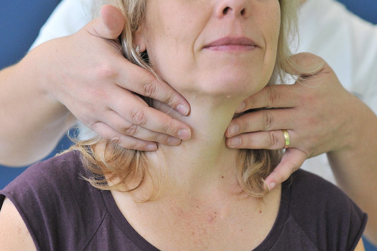 Upper body and neck of a woman. Hands feel the neck.