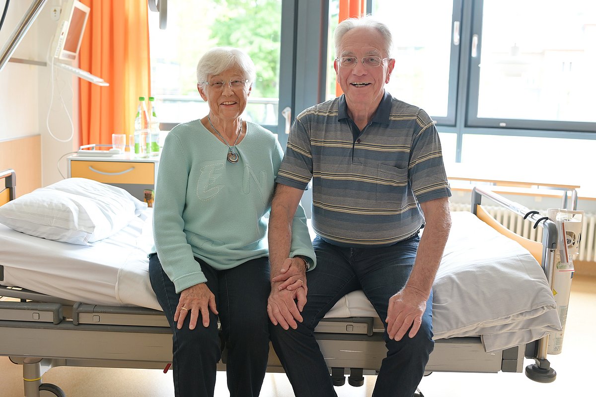 Mr. and Mrs. P. are sitting together on a hospital bed.