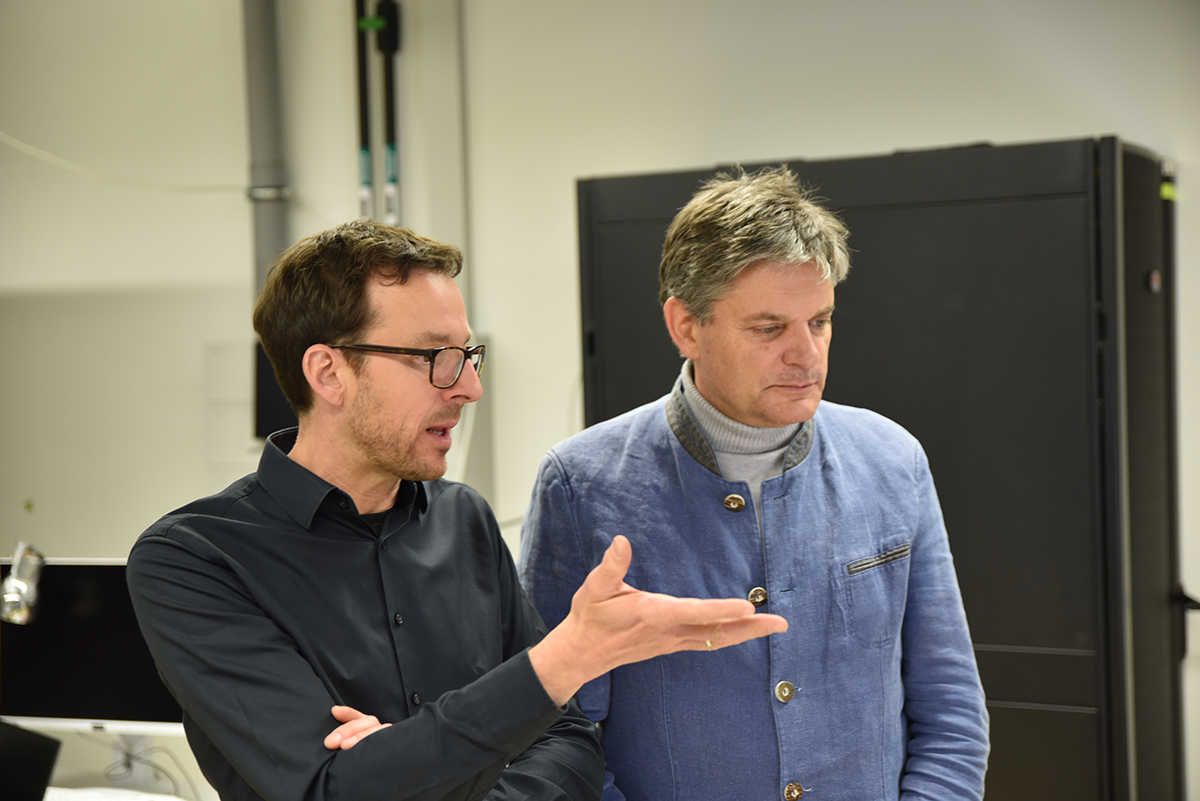 Professor Nicolas Vogel und FAU-Präsident Joachim Hornegger reden und schauen sich etwas gemeinsam an.