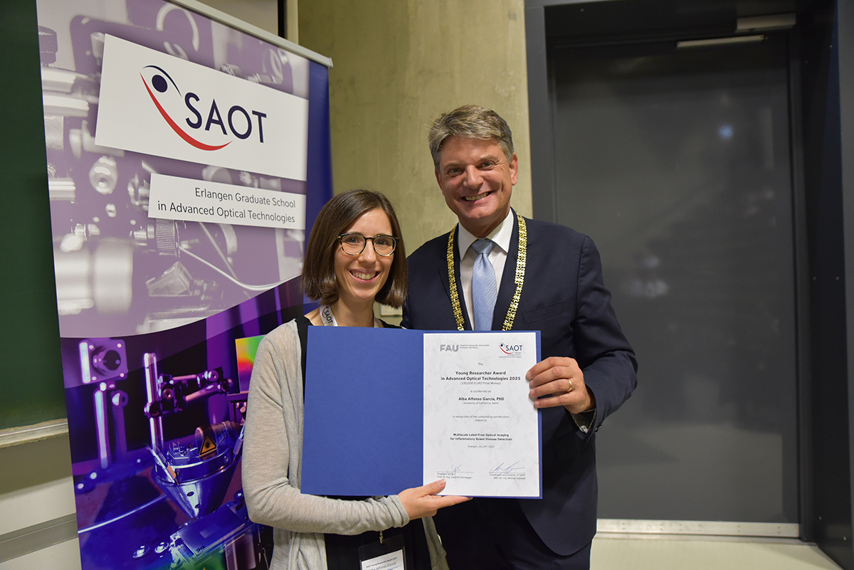 Dr. Alba Alfonso Garcia, a young woman with glasses and chin-length hair, presents her certificate. President Hornegger stands next to her.