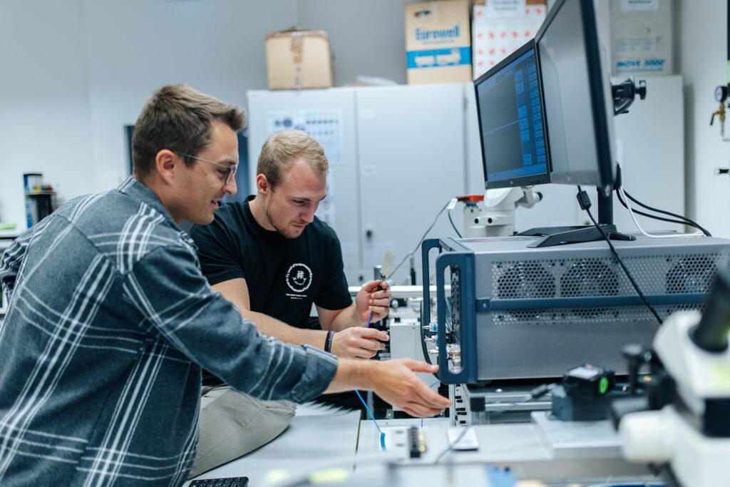 Two FAU researchers in a lab are sitting in front of computer screens.