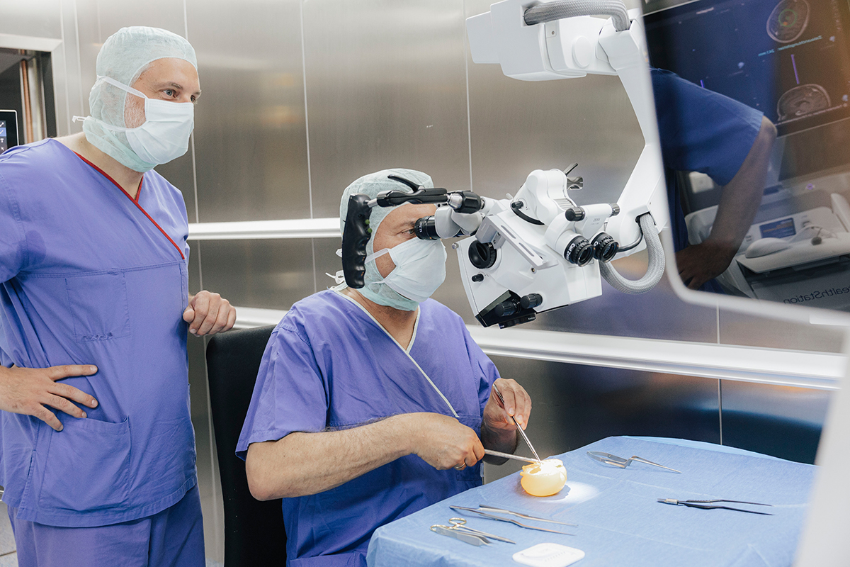 President Hornegger is sitting at a table and dissecting a bell pepper. Prof. Schnell is standing to his left.