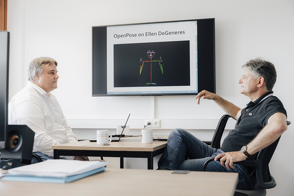 Peter Uhrig and Joachim Hornegger are sitting together at a table and talking.