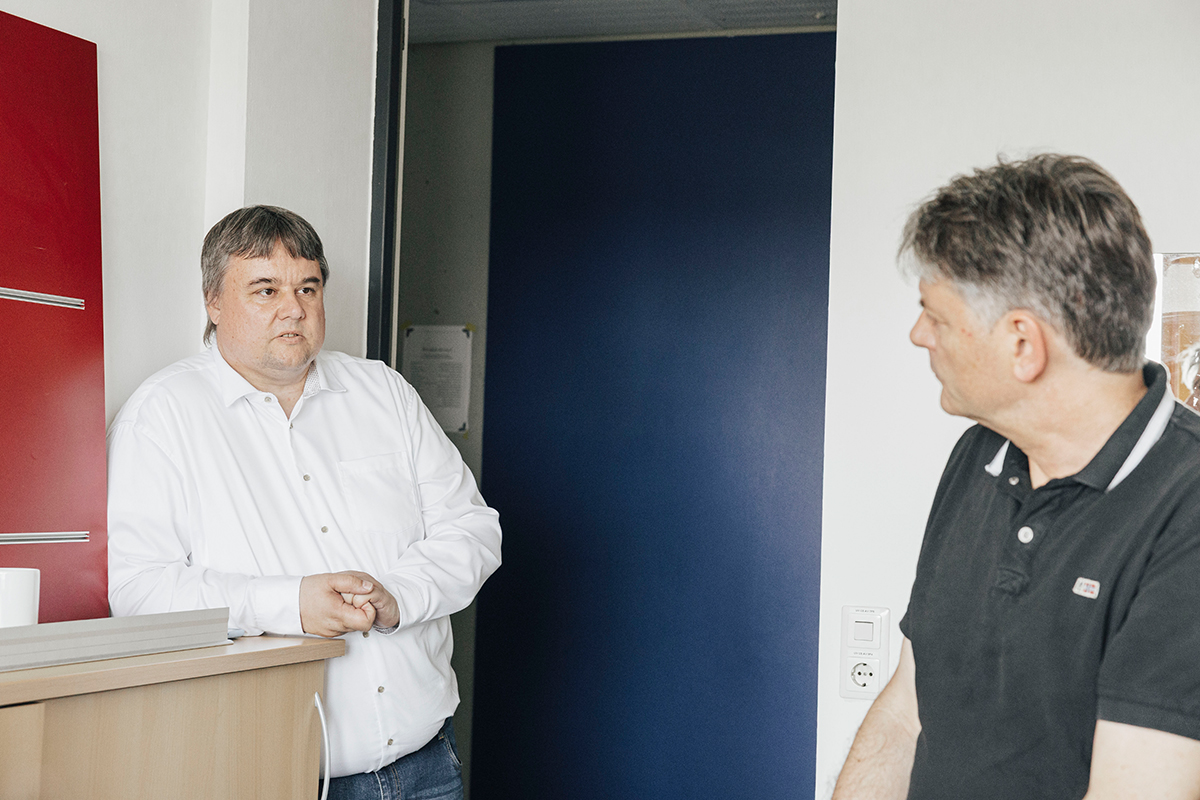 Prof. Uhrig and President Hornegger are standing together in a room talking, Hornegger has his back turned to the camera.