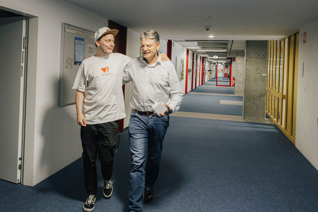 Prof. Reif and Joachim Hornegger are walking through the Economics Faculty together, talking.