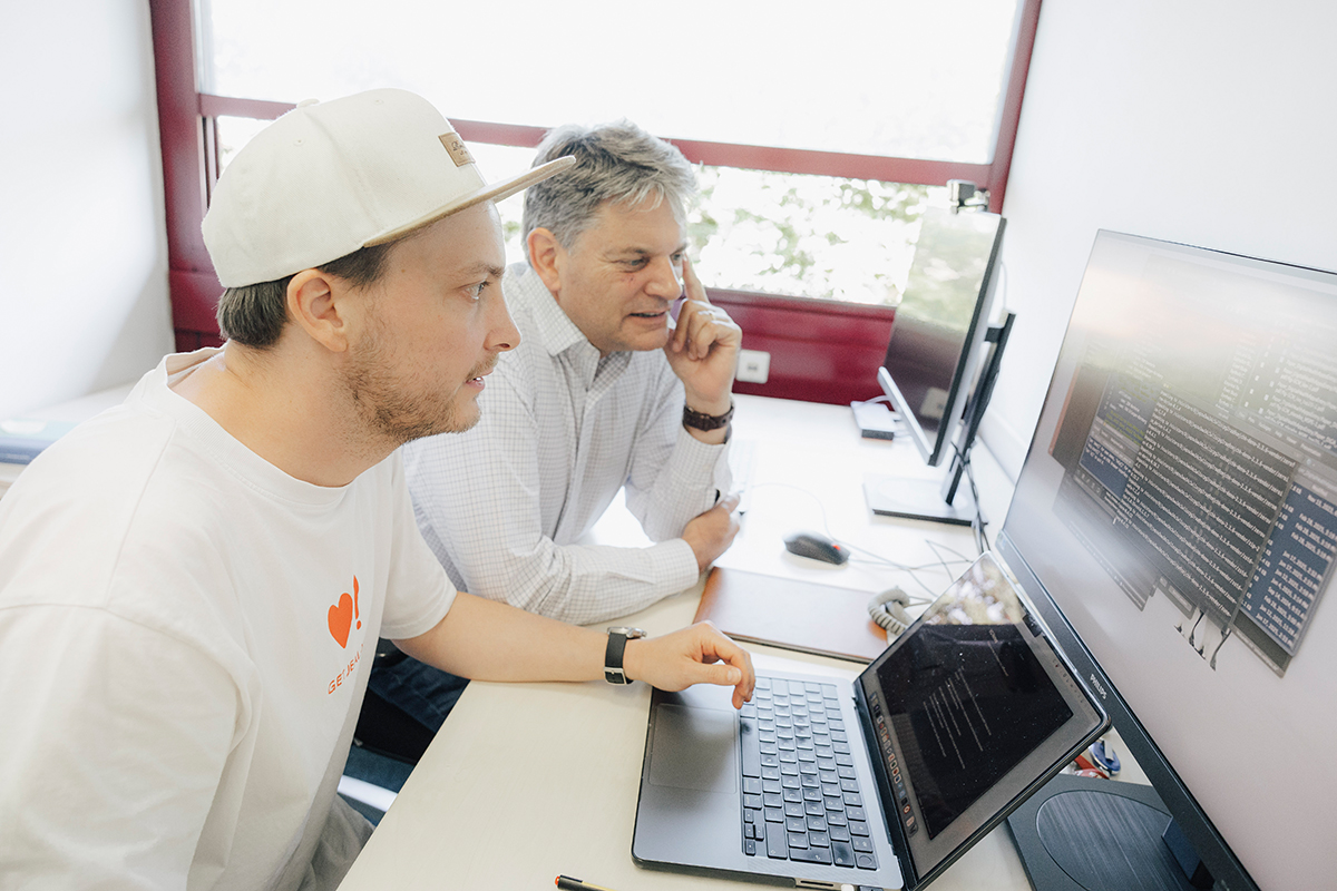 Hornegger and Reif are sitting in front of a laptop and looking at something on the screen.