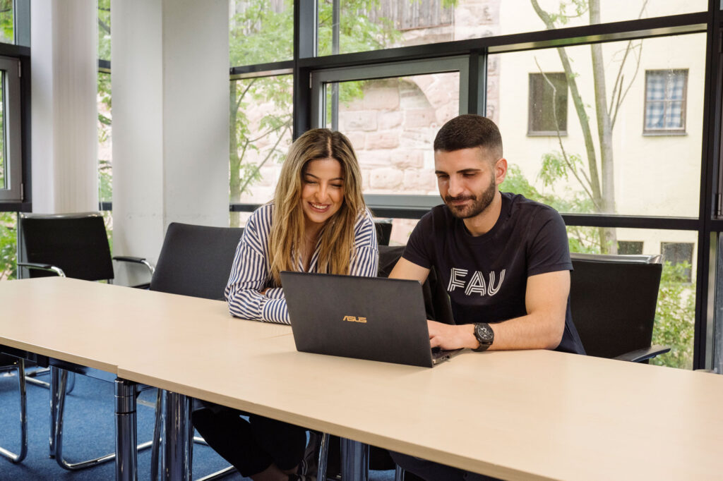 Zwei Personen vor Laptop