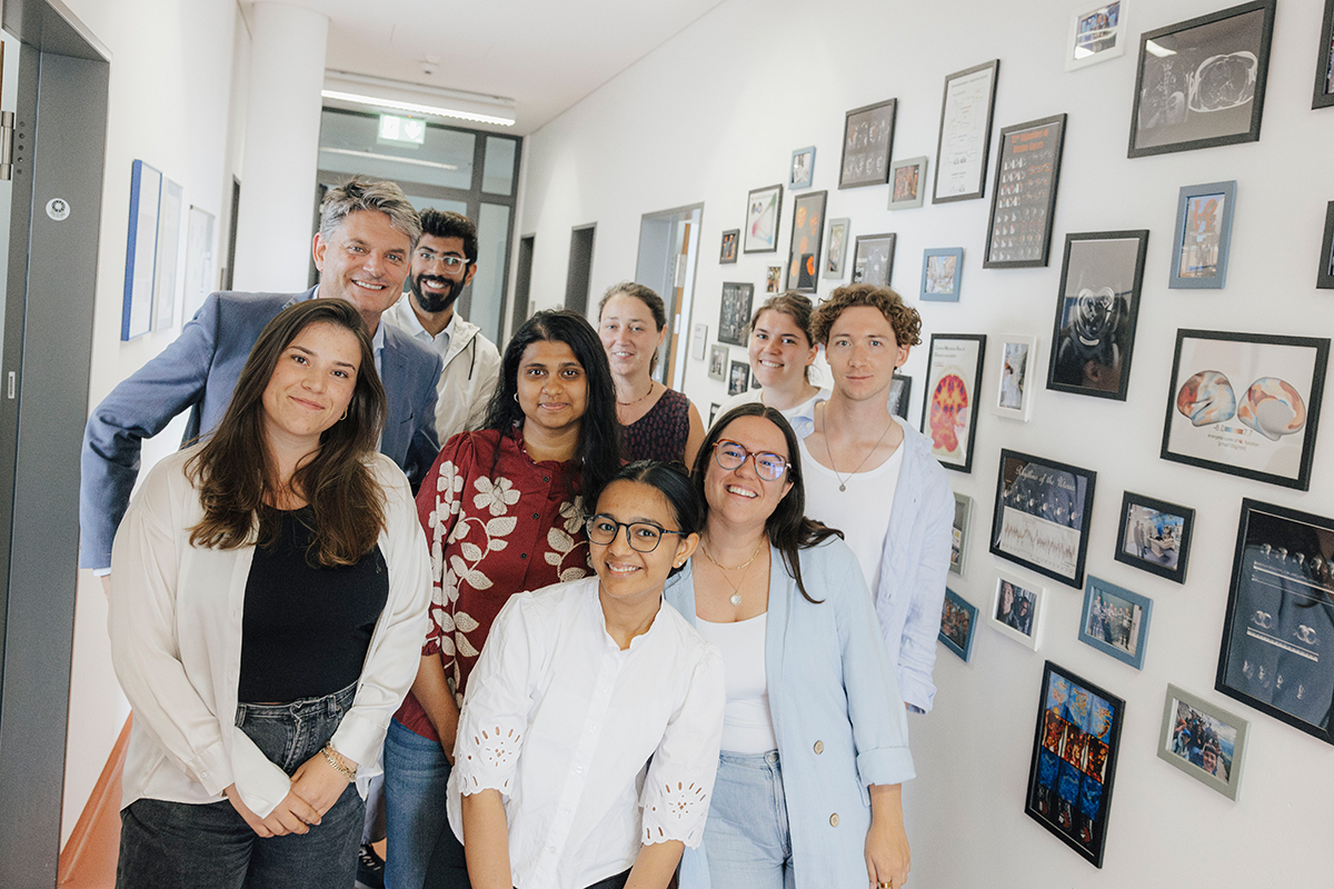 A group of researchers poses together with President Hornegger and Prof. Hutter in a corridor.