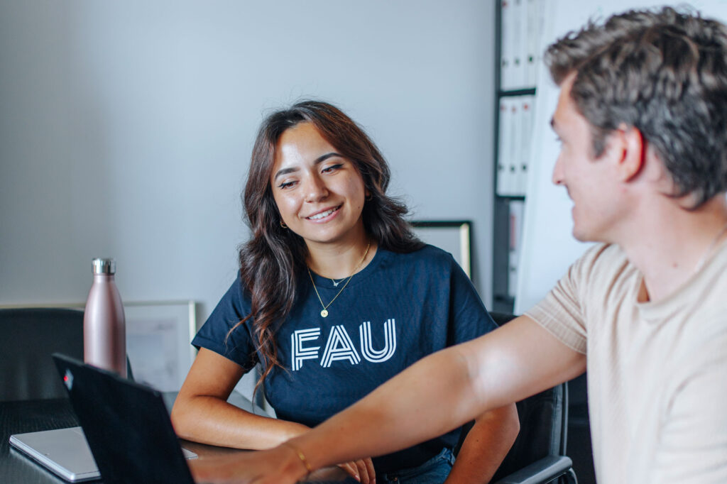 Frau zeigt einem Mann an einem Laptop etwas