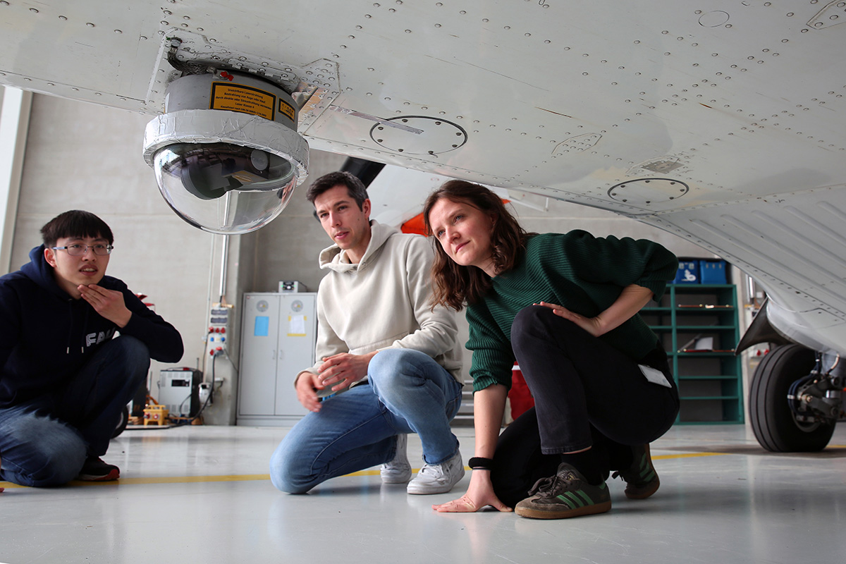 scientist examine a device under an airplane