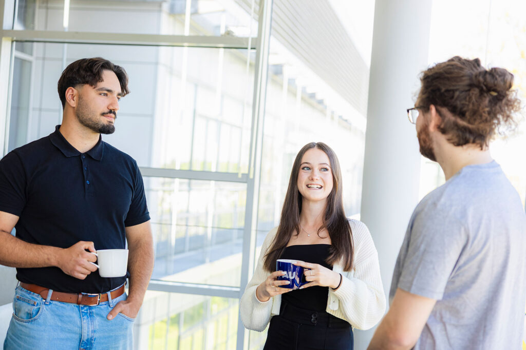 Drei Menschen trinken zusammen Kaffee und unterhalten sich.