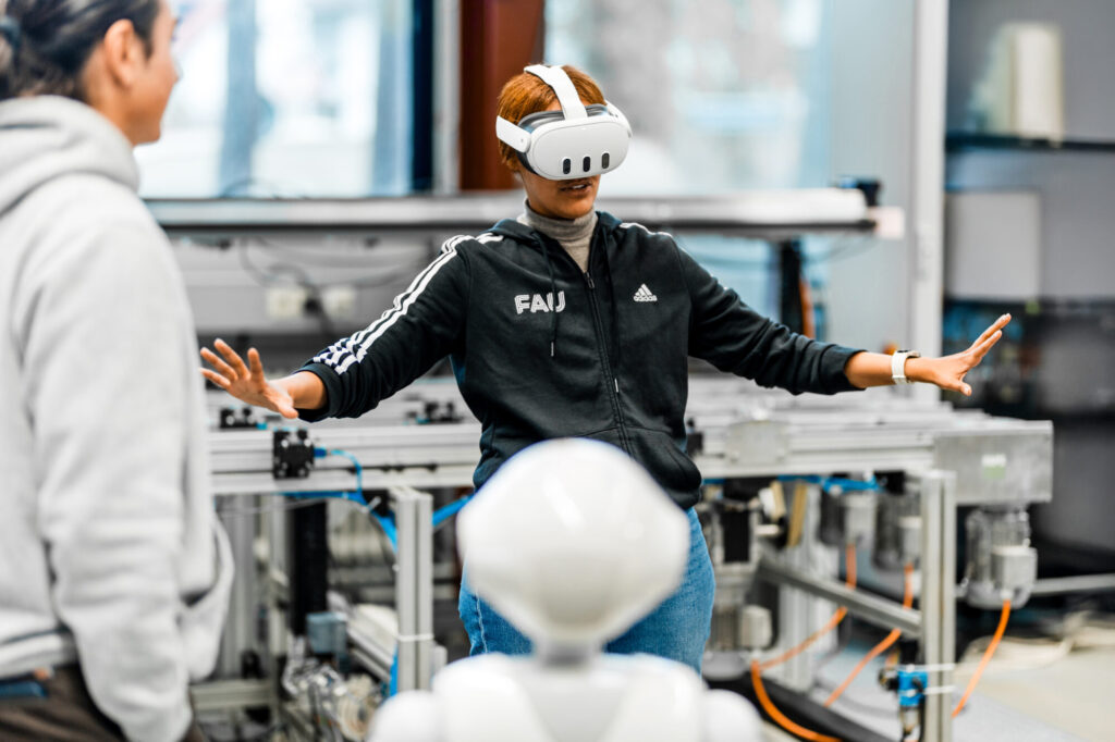 A man and a woman wearing VR goggles with a robot in a laboratory