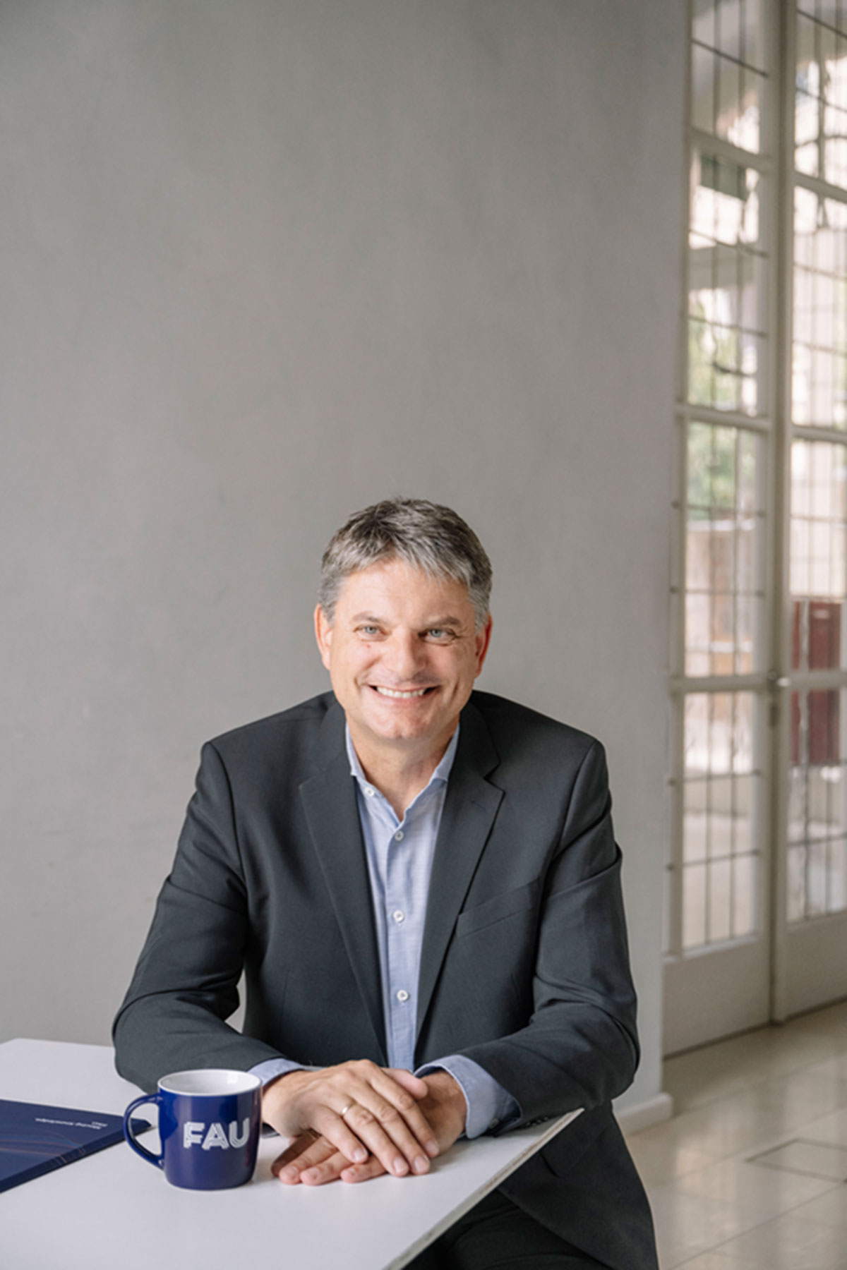 FAU-Präsident Joachim Hornegger sitzt an einem Tisch.