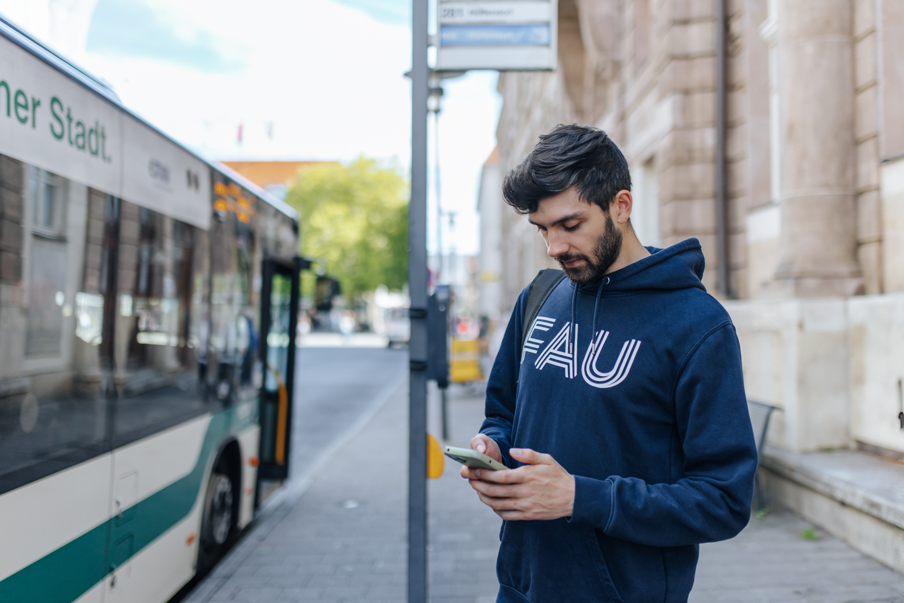 Mann steht an Bushaltestelle