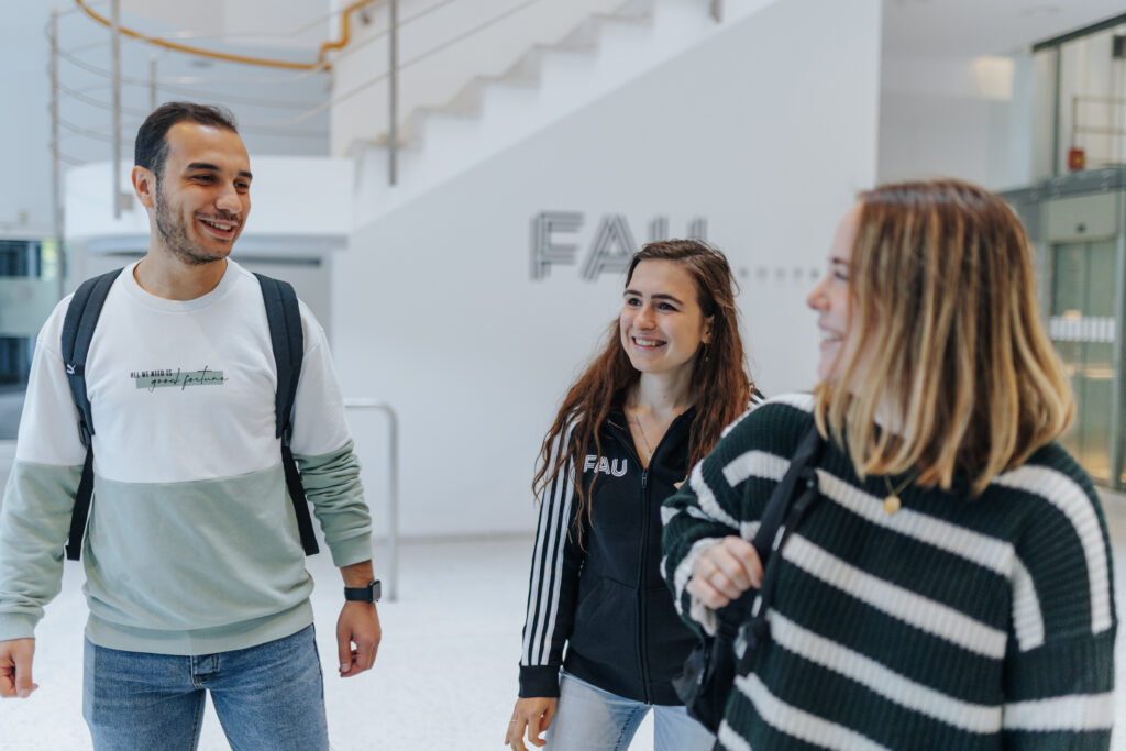 Three students are walking in the lobby of a building.