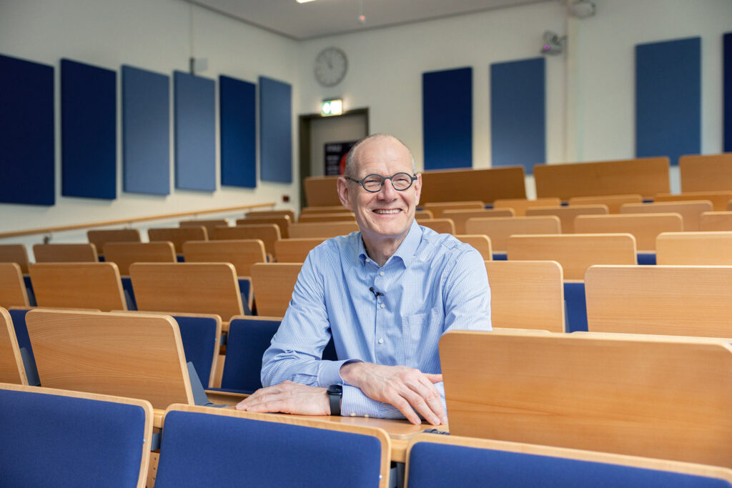 Bernd Montag sits in a lecture hall.
