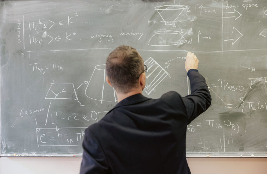 Dr. Wolfgang Wieland writes something on a blackboard.