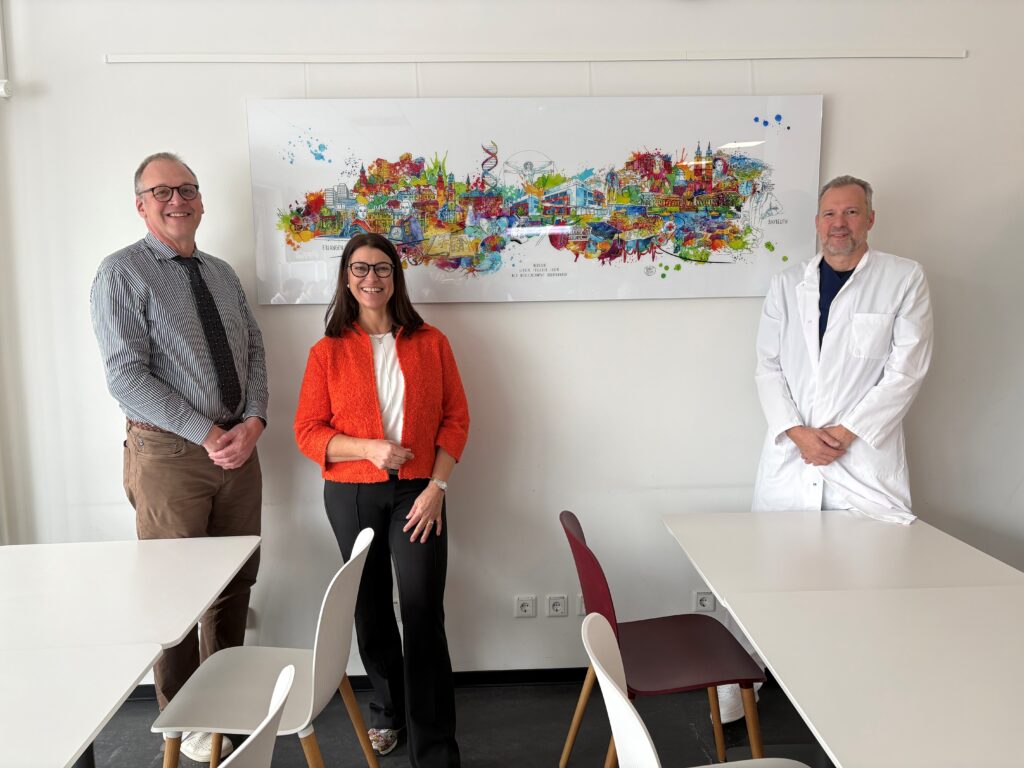 FAU medical professionals and artist Osten in front of the artwork for the FAU Medical Campus Upper Franconia.
