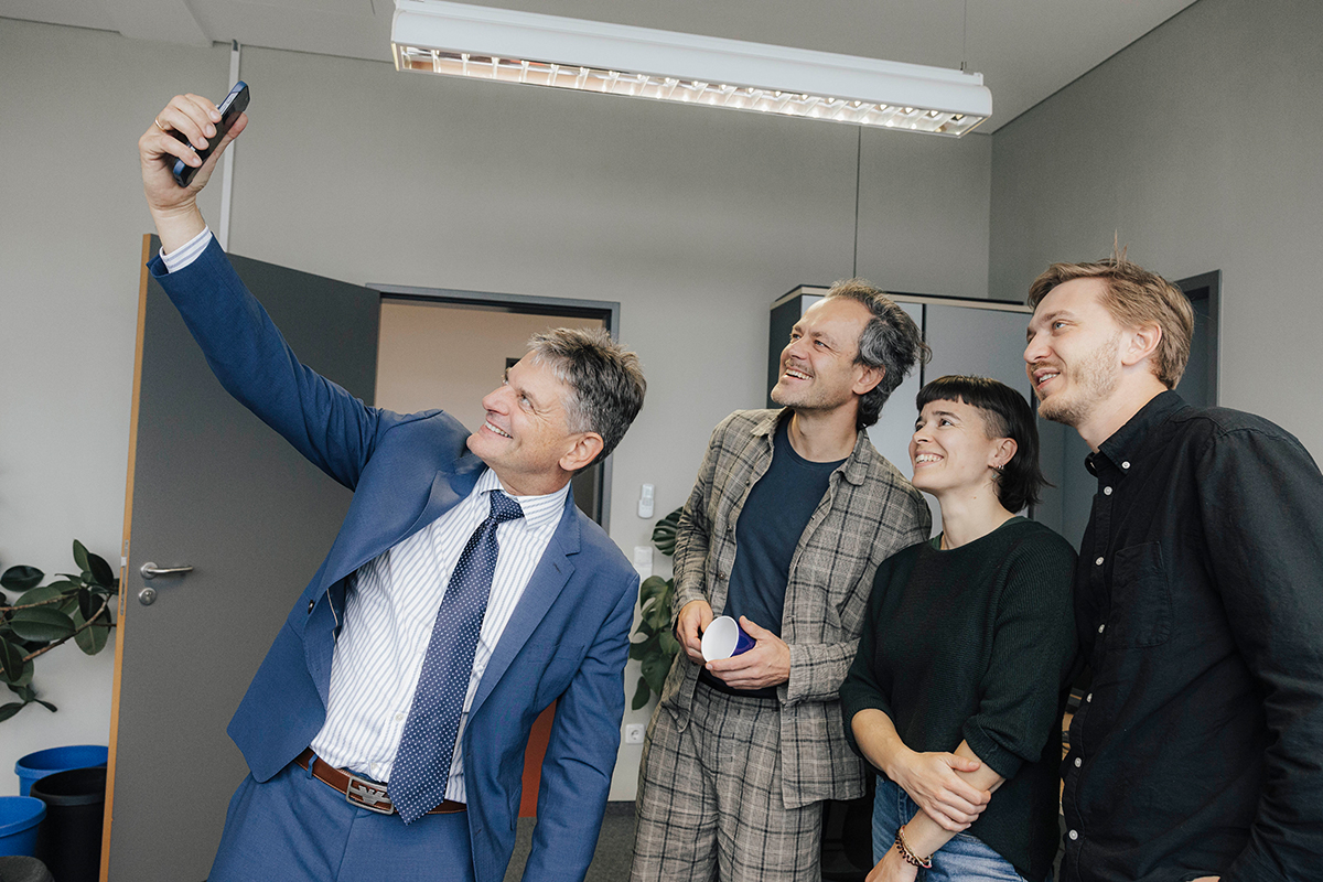 President Hornegger, Prof. Riedl and his team take a selfie in an office.