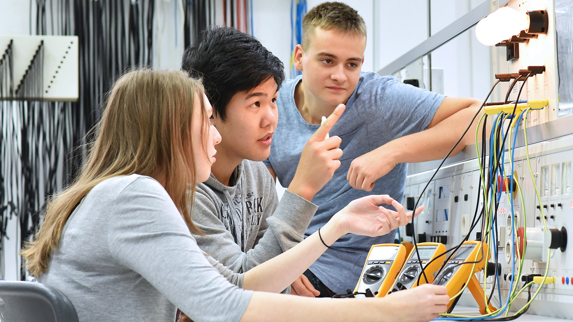 Schülerinnen und Schüler vor einem Schaltkasten