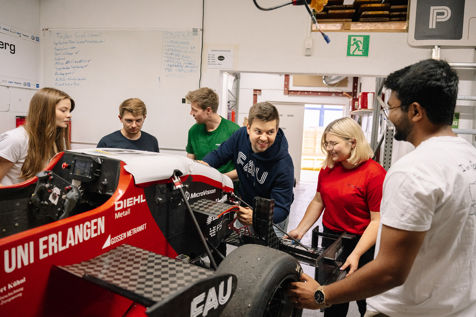 Students in a garage with a car.