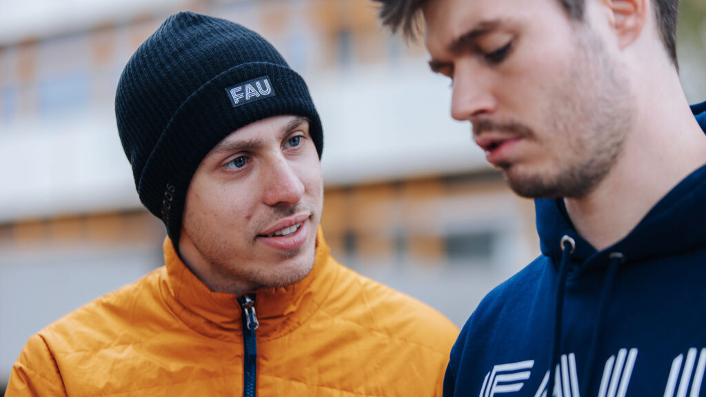 Two scienists outside. One of them is wearing a FAU beanie.