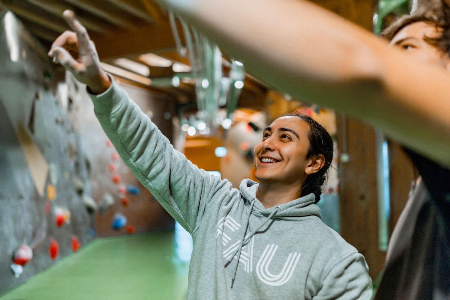 Studierende in Boulderhalle zeigen auf Route