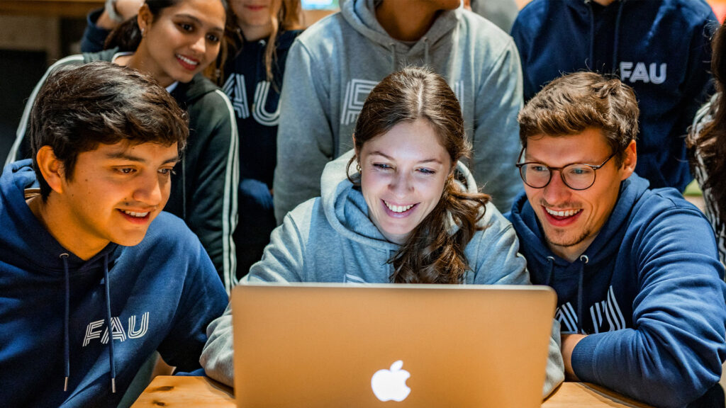 Students sitting in front of a laptop.