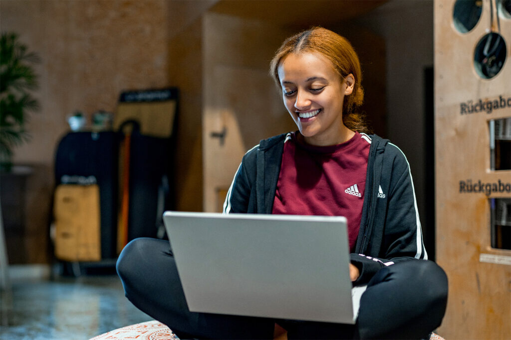 Stundentin im Schneidersitz mit Laptop