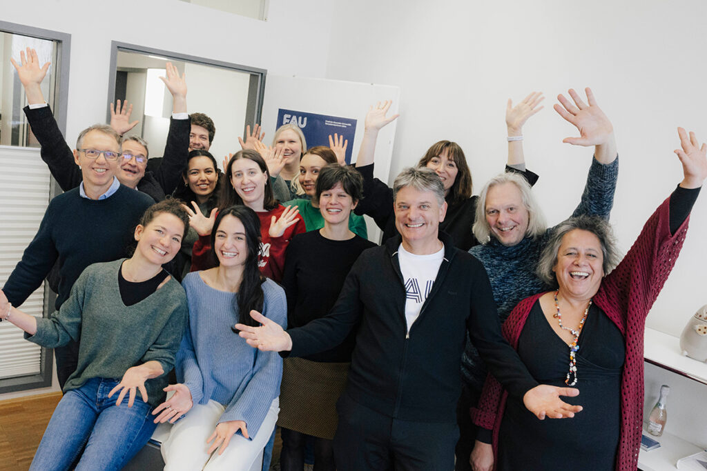 Joachim Hornegger, Svenja Bedenlier, and Bedenlier's team are all standing in a room, posing for a group photo. They are all smiling and have their arms raised slightly.