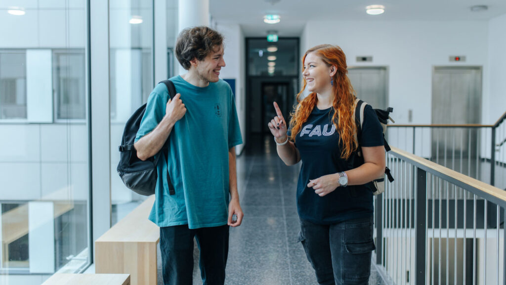 Two students talking to each other in a stairway.