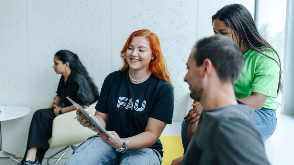 Students sit together, looking in a tablet.