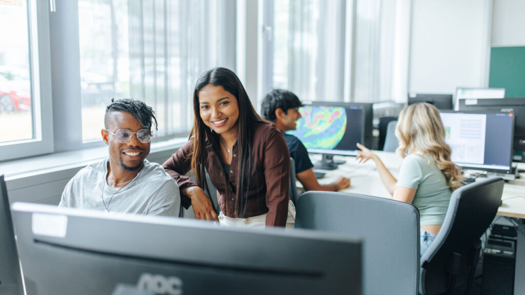 Four students sitting together at some computers.