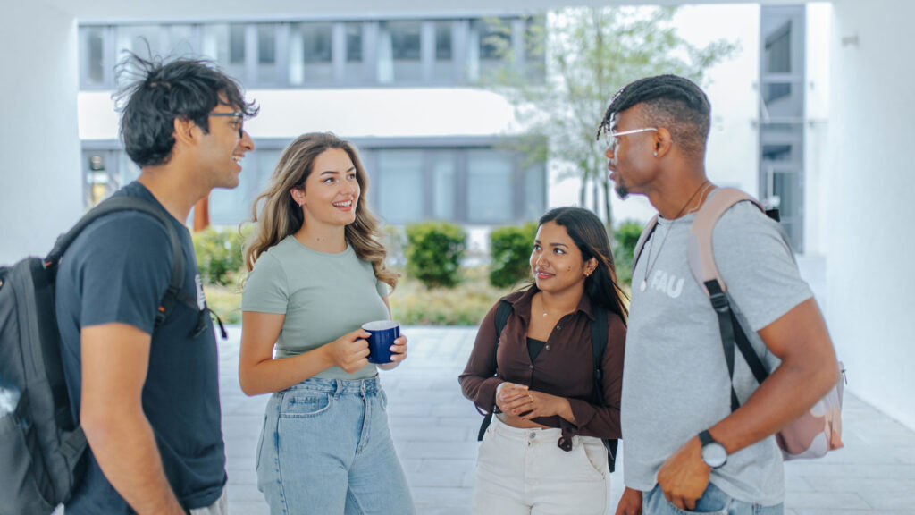 Four students in front of a FAU building.