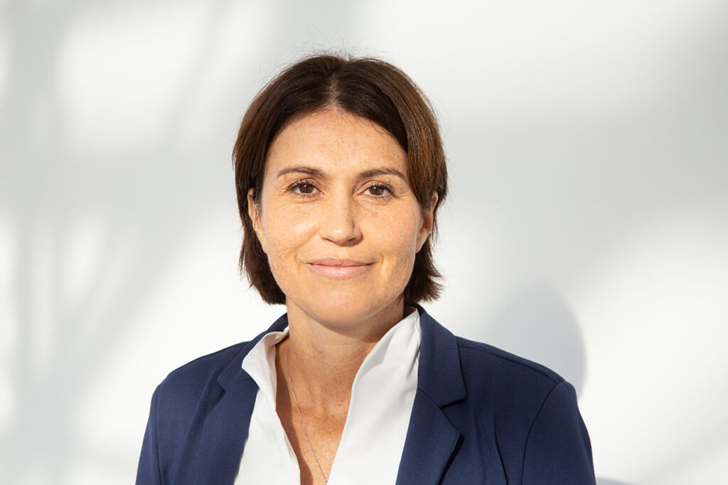 Prof. Sarah Kittel-Schneider, a woman with a brown bob and brown eyes, faces the camera and smiles. She is wearing a blazer and shirt.