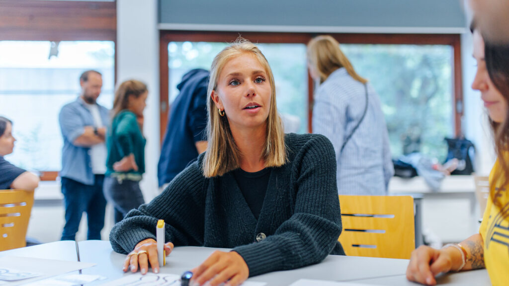 A student sitting at a table holding a pen.